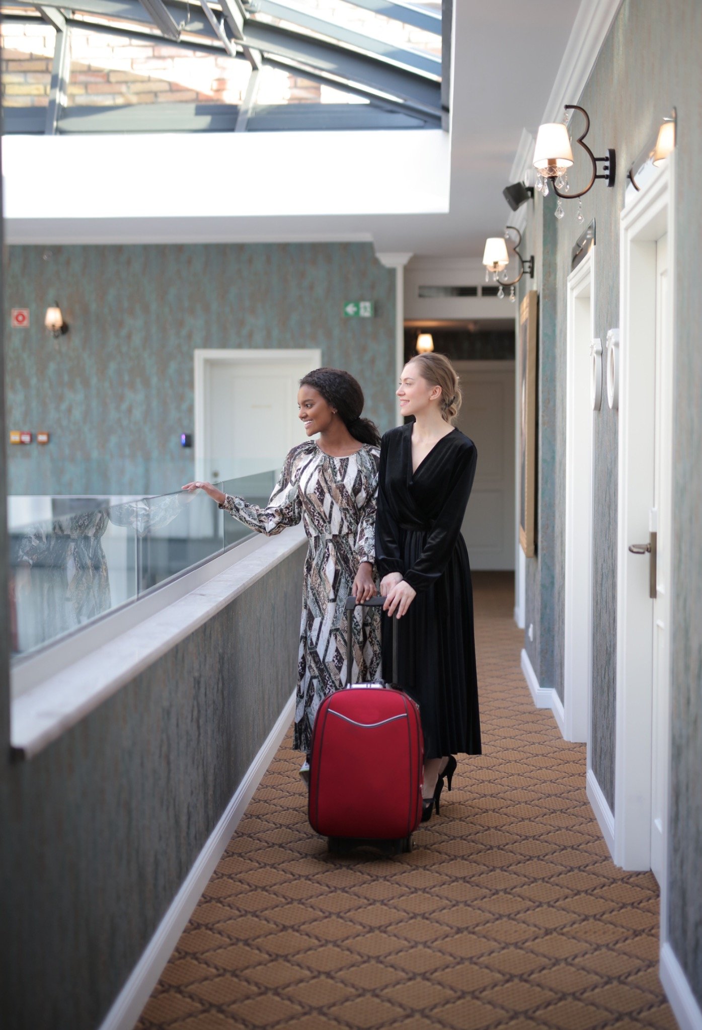 Dos viajeras en el interior de un alojamiento con una maleta